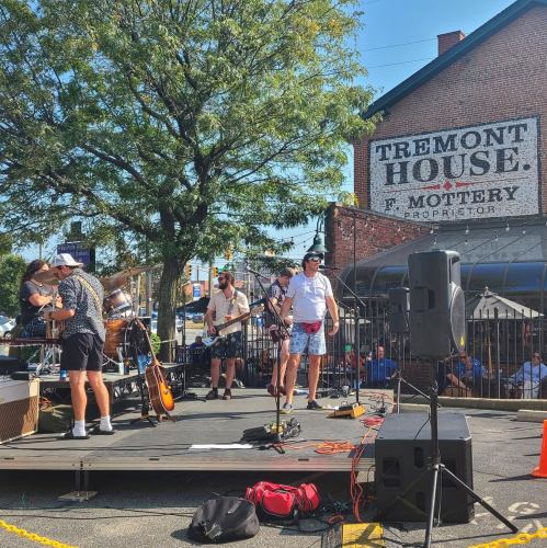 A live band performs on an outdoor stage in front of the Tremont House, with a crowd enjoying the music.