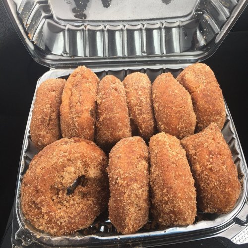 A container filled with freshly baked, cinnamon-sugar coated donuts arranged neatly.