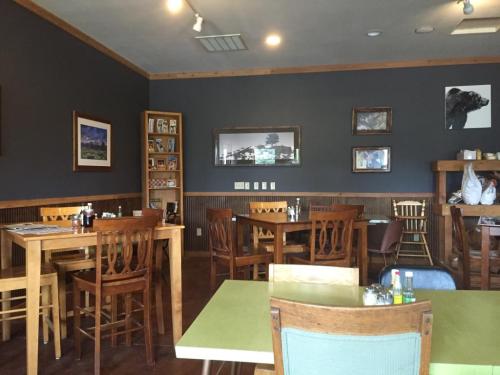 Cozy restaurant interior with wooden tables, chairs, and framed artwork on dark walls. A shelf displays various items.