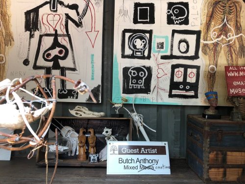 Art installation featuring mixed media pieces by Butch Anthony, with skeletons and various artistic elements displayed.