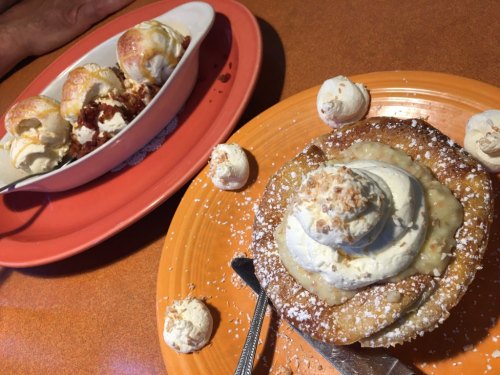 A dessert plate featuring a large cookie topped with whipped cream and a scoop of ice cream in the background.