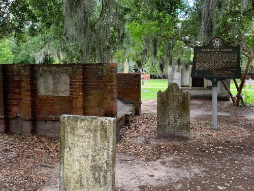 A historic grave site with several headstones surrounded by trees and a sign labeled "Duellist's Grave."