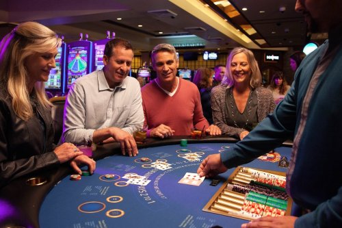 A group of four people enjoying a game at a casino table, with chips and cards in a lively atmosphere.