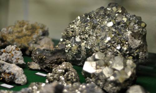 A collection of various minerals and crystals, including shiny pyrite, displayed on a green surface.