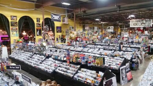 A spacious record store filled with rows of CDs and vinyl, featuring colorful posters and vintage decor.