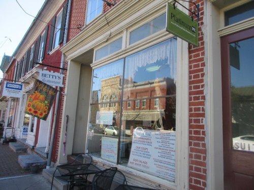 A brick storefront with large windows displaying restaurant menus and a sign for "Platinum PR."