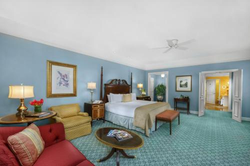 A spacious hotel room featuring a king bed, seating area, and bright blue walls with decorative artwork.