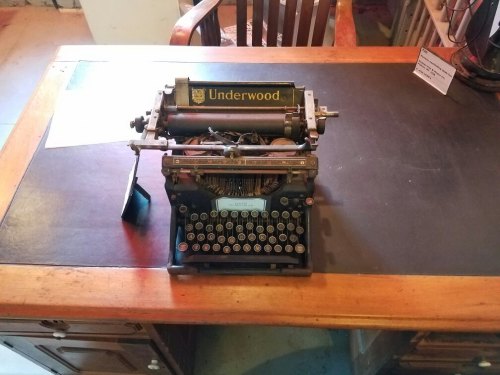 An antique Underwood typewriter on a wooden desk with a leather writing surface.