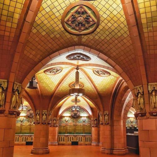 Interior of a grand, ornate hall with arched ceilings, intricate tile work, and decorative sculptures. Warm lighting enhances the ambiance.