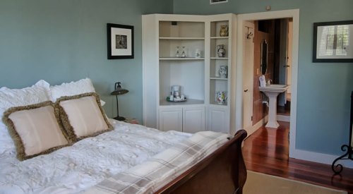 Cozy bedroom with a bed, decorative pillows, and a doorway leading to a bathroom with elegant decor.