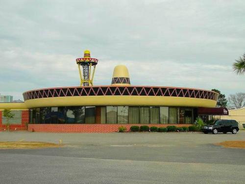 A unique, round building with a colorful roof and decorative elements, set against a cloudy sky.