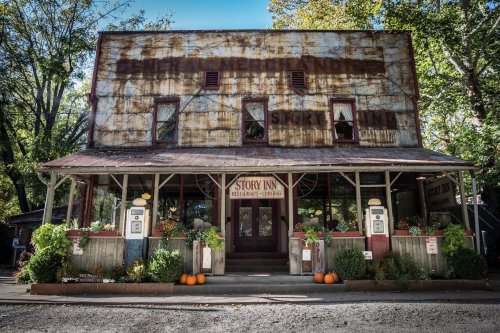 A rustic building with a weathered facade, featuring a sign for "Story Inn" and surrounded by autumn decorations.