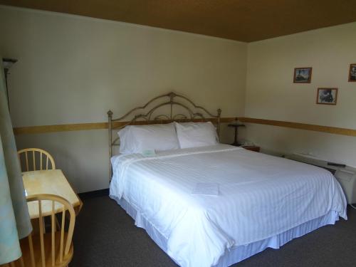 A simple hotel room featuring a large bed, a small dining table, and framed pictures on the wall.