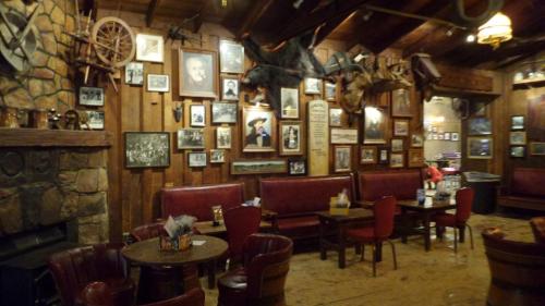 Cozy restaurant interior with wooden walls, vintage photos, and rustic decor, featuring leather seating and a stone fireplace.