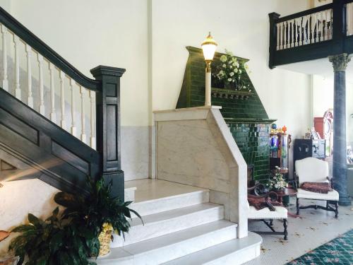Elegant interior featuring a staircase, green tiled fireplace, and vintage furniture in a well-lit space.