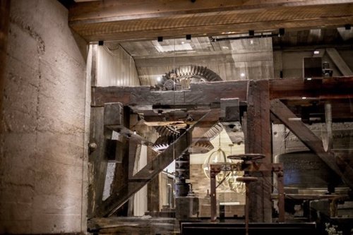 Close-up of vintage machinery with wooden beams and gears, showcasing industrial design in a rustic setting.