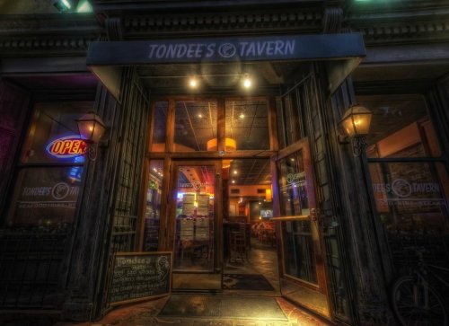 Entrance of Tondee's Tavern, featuring open doors, warm lighting, and a welcoming sign.