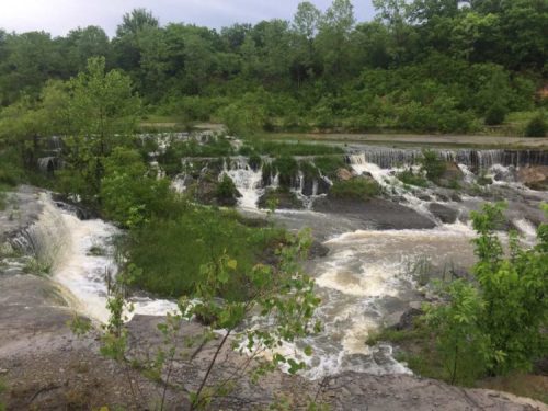A serene landscape featuring cascading waterfalls surrounded by lush greenery and trees.