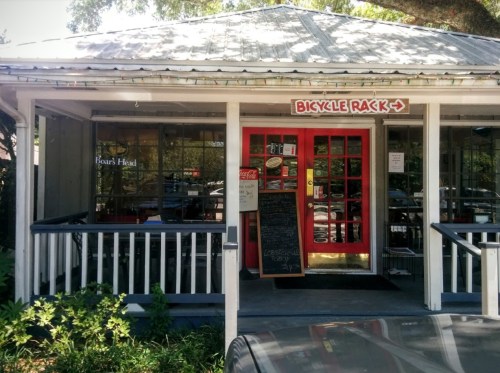 A quaint restaurant entrance with red doors, a bicycle rack sign, and a chalkboard menu outside.