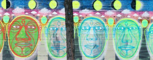 Colorful mural featuring four stylized faces with vibrant outlines, set against a backdrop of celestial elements.