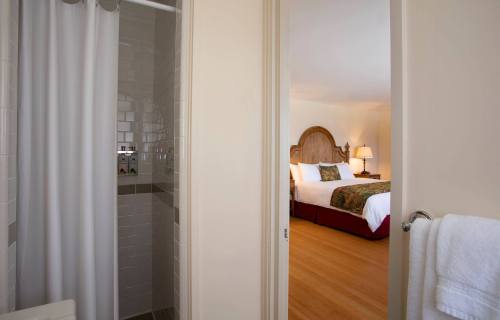 View from a bathroom doorway into a cozy hotel room with a bed and warm lighting.