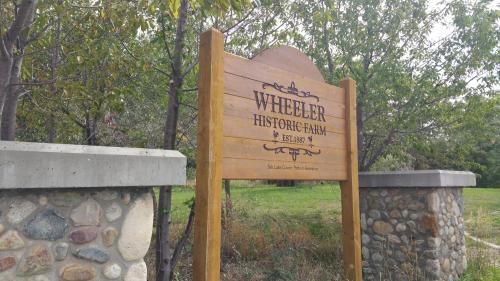 Sign for Wheeler Historic Farm, established in 1886, surrounded by trees and stone pillars.