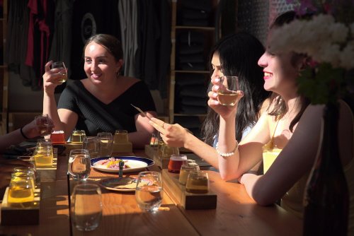 A group of friends enjoying drinks and food at a table, smiling and chatting in a warm, inviting setting.