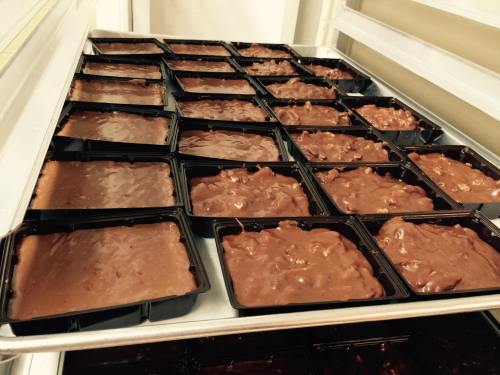 Trays filled with chocolate fudge in black containers, arranged neatly in a refrigerator.
