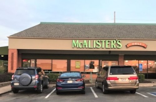 Exterior of a McAlister's Deli restaurant with three parked cars in front.