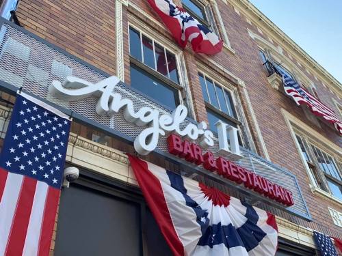 Sign for "Angelo's II Bar & Restaurant" with American flags and patriotic bunting on a brick building.