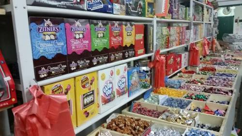 A colorful display of various candies and chocolates on shelves and tables in a candy store.