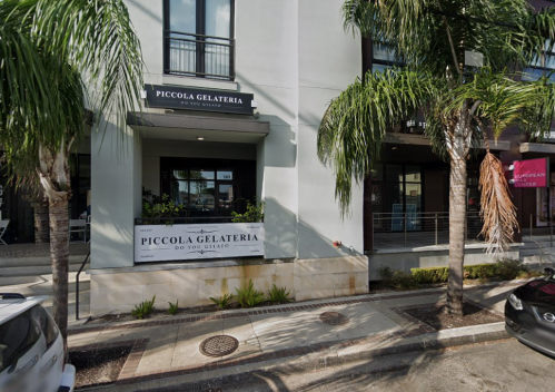 Exterior of Piccola Gelateria with palm trees, featuring a sign that reads "Piccola Gelateria - Do You Gelato?"