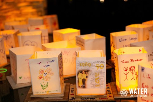 Colorful paper lanterns with drawings and messages, glowing softly at the Water Lantern Festival.