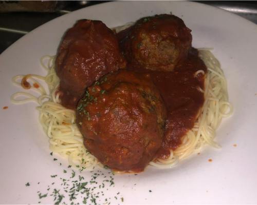 A plate of spaghetti topped with three large meatballs and marinara sauce, garnished with parsley.