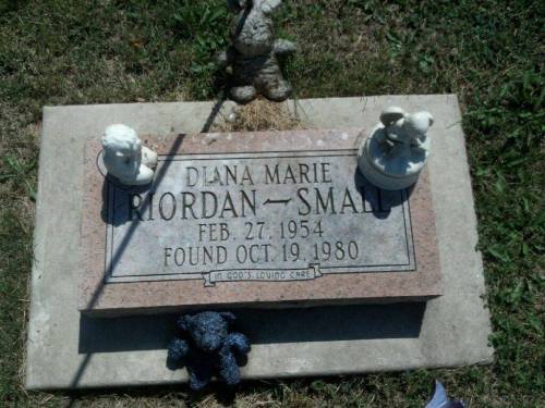 Gravestone of Diana Marie Riordan-Small, with decorative figurines and a stuffed animal, dated February 27, 1954 - October 19, 1980.