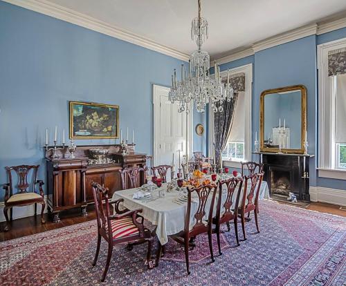 Elegant dining room with a chandelier, a large table set for a meal, and blue walls adorned with classic decor.