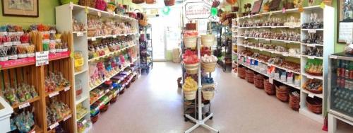 A colorful candy shop interior with shelves filled with various candies and treats, and baskets lining the walls.