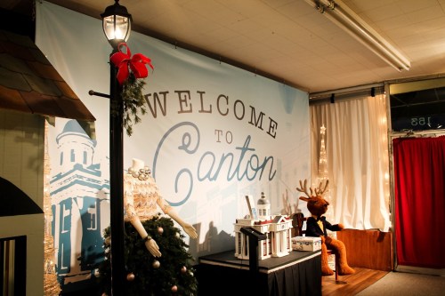A festive display featuring a "Welcome to Canton" sign, a decorated tree, and a reindeer figure in a cozy setting.
