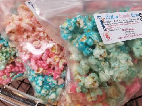Colorful bags of cotton candy popcorn in pink and blue, labeled with ingredients and manufacturer information.