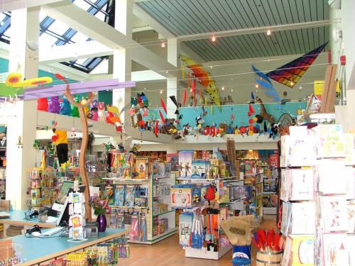 Brightly colored toy store interior filled with shelves of toys, games, and decorations hanging from the ceiling.
