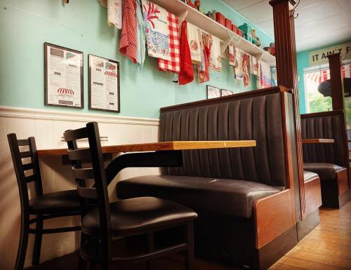 Cozy diner interior with black booths, wooden tables, and colorful vintage decor on the walls.