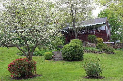 A charming house surrounded by blooming trees and shrubs, with a grassy lawn and stone steps leading to the entrance.