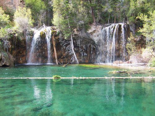A serene landscape featuring cascading waterfalls into a clear, turquoise pool surrounded by lush greenery.