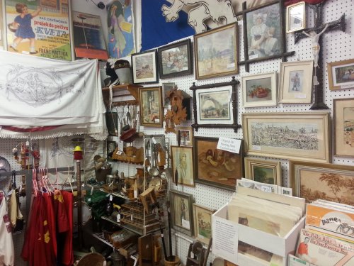 A cluttered antique shop wall filled with framed art, vintage items, and various collectibles.