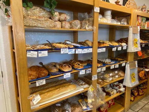 A wooden shelf filled with various baked goods, including bread, pastries, and cookies, neatly displayed with price tags.