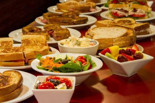A variety of sandwiches and salads arranged on plates, featuring colorful vegetables and fresh ingredients.