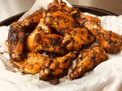 A platter of grilled chicken wings, seasoned and cooked to a crispy, golden-brown perfection.