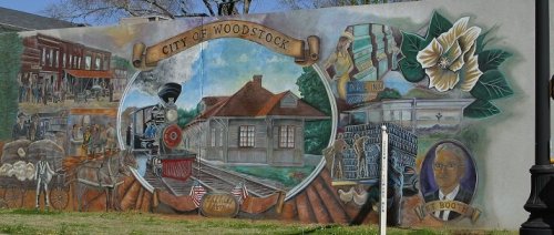 Mural depicting the history of Woodstock, featuring a train, buildings, and local landmarks.