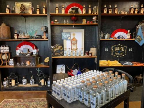 A display at Bard Distillery featuring bottles, merchandise, and shelves adorned with various items and decorations.