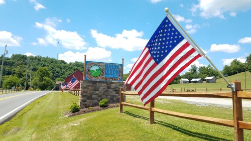 A sign for Mason Dixon with an American flag, set against a blue sky and green hills.